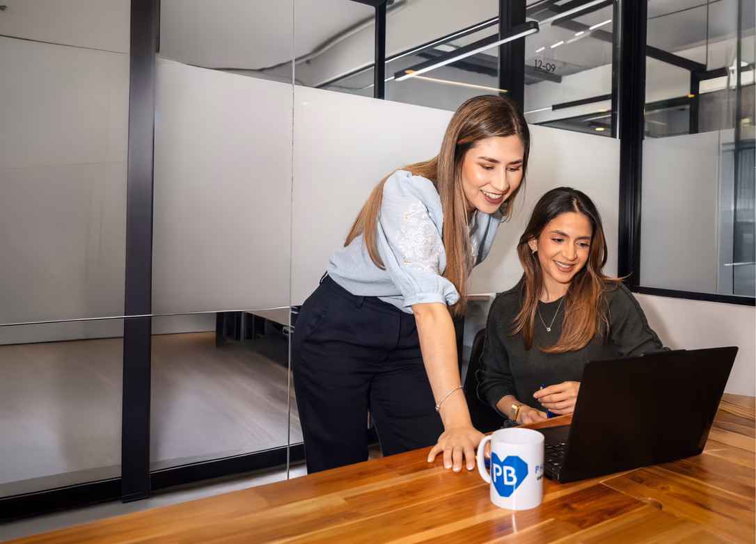 Pharmbills team members collaborating at a laptop in a glass-walled office
