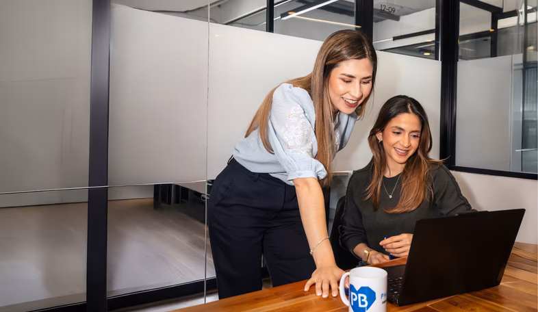 Pharmbills team members collaborating at a laptop in a glass-walled office